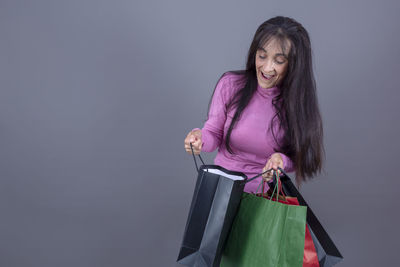 Portrait of young woman holding box against blue background