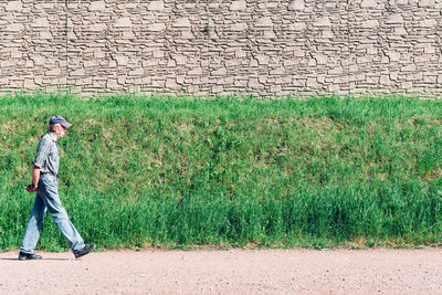 Side view of man walking on road by plants