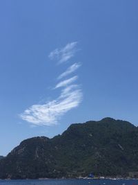 Scenic view of sea and mountains against blue sky