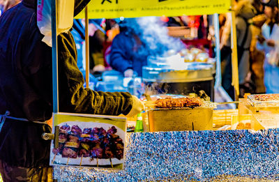 Midsection of person selling skewers at street market
