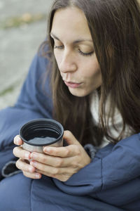 Woman wrapped in blanket blowing on coffee