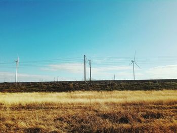 Electricity pylon on field against clear blue sky