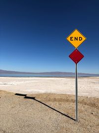 Road sign in desert against clear blue sky