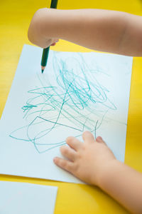 High angle view of kid scribbling on paper at table