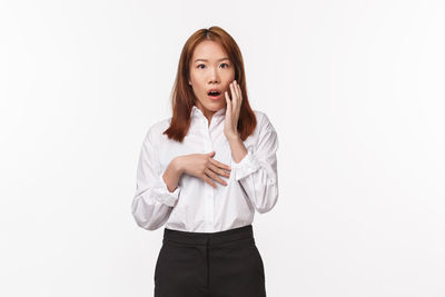 Portrait of young woman standing against white background