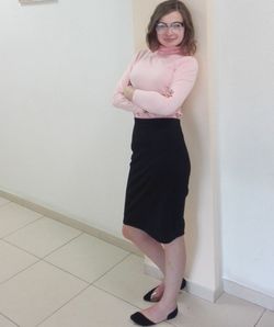 Portrait of a smiling young woman standing against wall