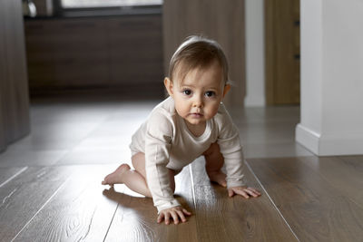 Portrait of cute boy sitting on hardwood floor at home