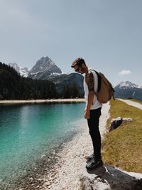 Full length of young woman standing by lake against mountains