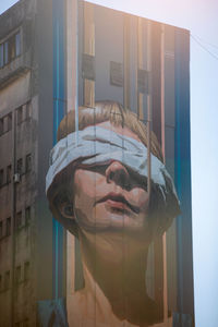 Portrait of young woman against building in city