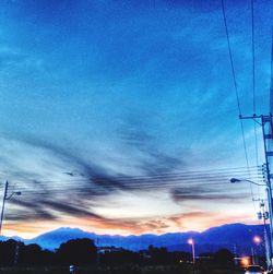 Electricity pylon against cloudy sky