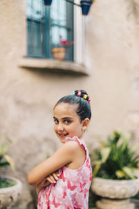 Portrait of cute smiling girl standing against wall
