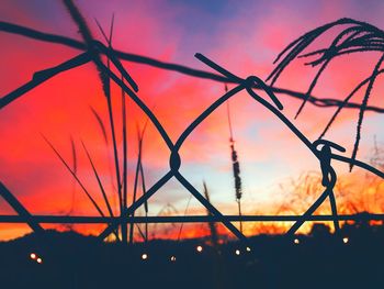 Close-up of silhouette fence against orange sky