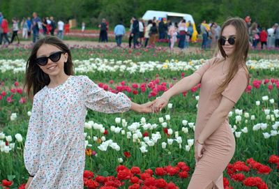 Rear view of women in traditional clothing while walking on street amidst flowering plants