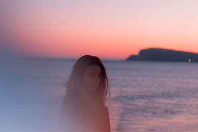 Portrait of woman standing against sea during sunset