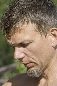 Close-up of shirtless mature man looking down in sunlight