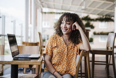 Portrait of young woman using phone while sitting on table
