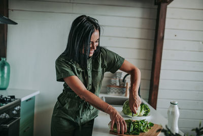 Midsection of woman standing in kitchen at home