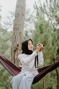 Portrait of young woman standing against trees
