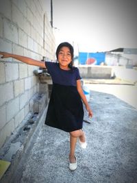 Portrait of smiling girl standing against wall