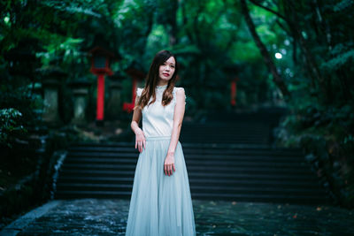 Portrait of young woman standing against staircase