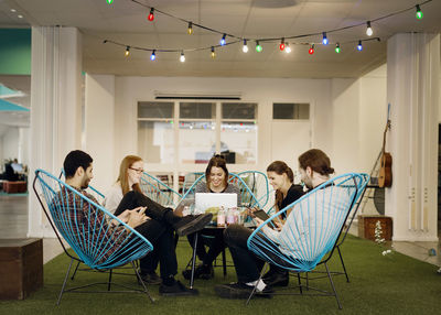 Creative business people using technologies in office canteen