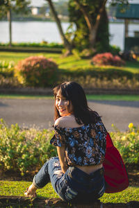 Portrait of beautiful young woman sitting at park
