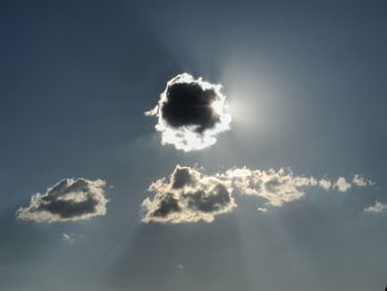 Low angle view of sunlight streaming through clouds