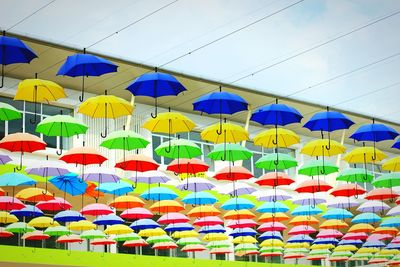 Low angle view of colorful umbrellas hanging against sky