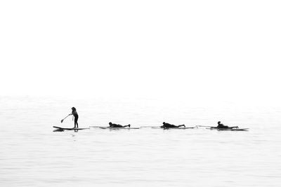 Silhouette people on sea against sky