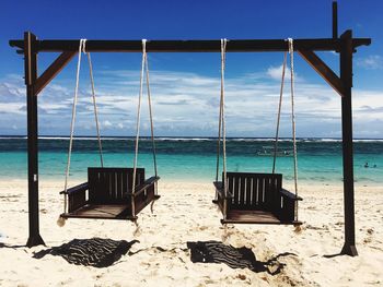 Swings at beach against blue sky