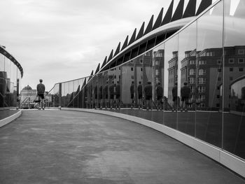 Rear view of man walking on bridge against sky