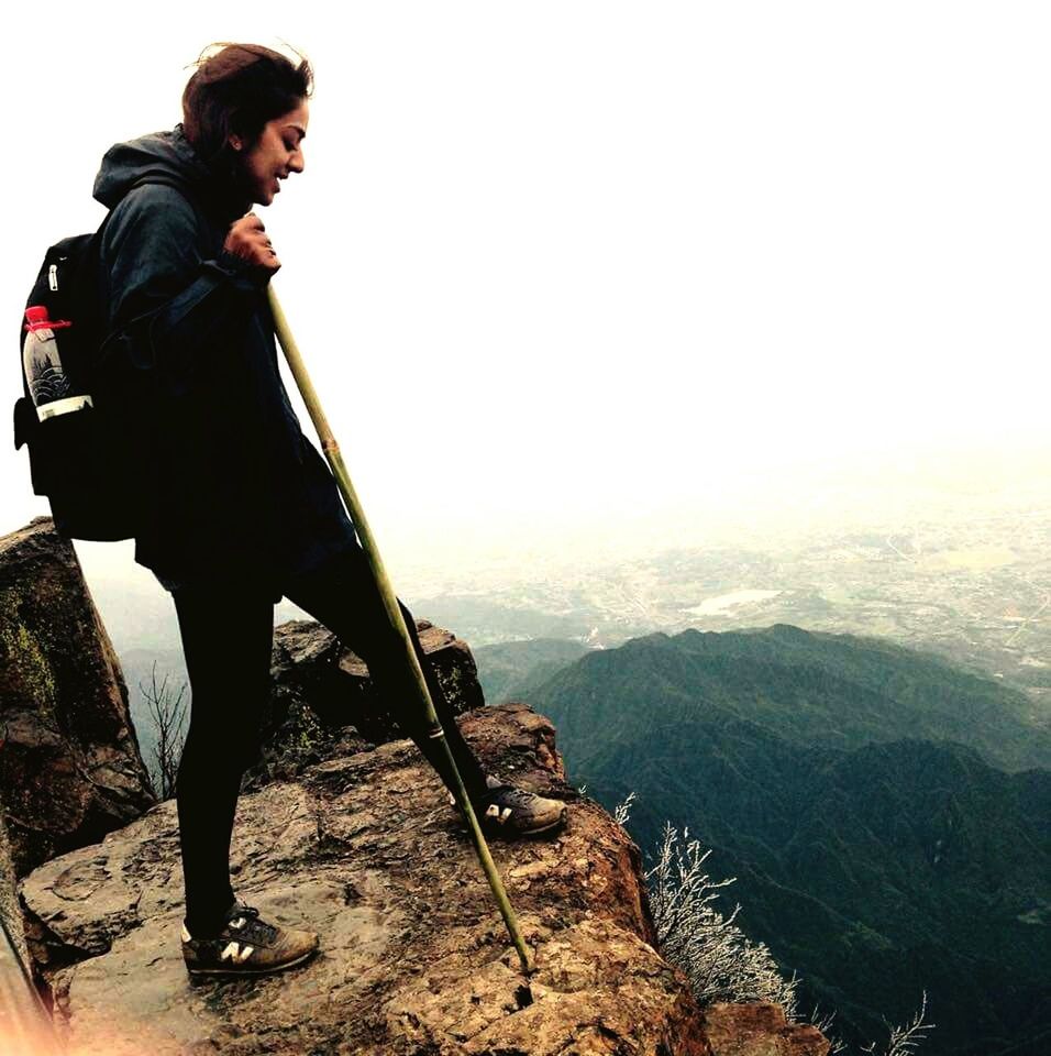 MAN STANDING ON MOUNTAIN AGAINST SKY