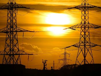 Silhouette of electricity pylon at sunset