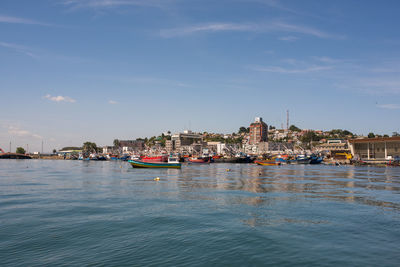 River by buildings in city against sky