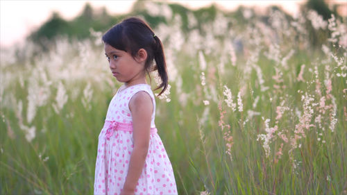 Side view of thoughtful girl standing against plants