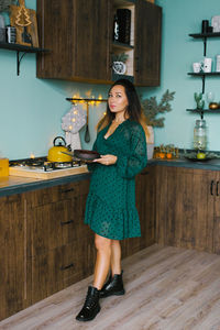 Stylish beautiful brunette woman holds a christmas cake in her hands in the kitchen at home