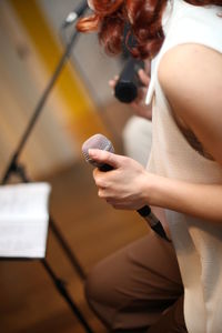 Midsection of woman holding microphone