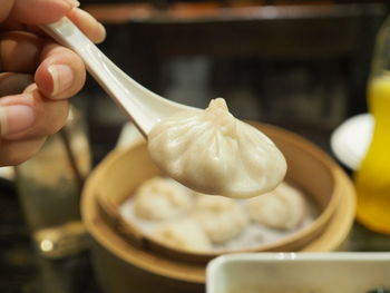 Close-up of cropped hand holding chinese dumpling on spoon