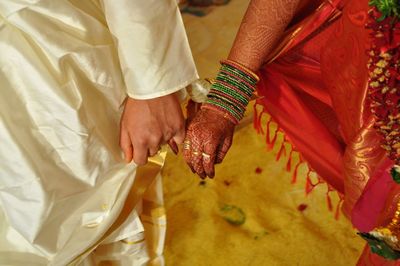 Midsection of indian bridal couple holding hands during wedding ceremony