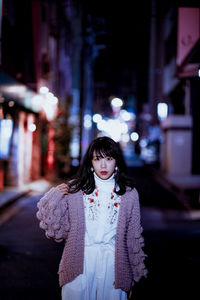 Young woman on illuminated street at night