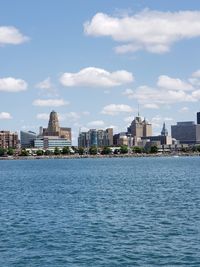 Sea by buildings in city against sky