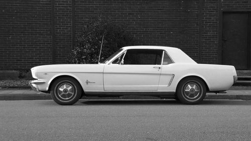 Side view of vintage car on street against brick wall