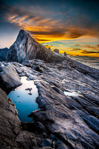 Scenic view of sea by snowcapped mountains against sky during sunset