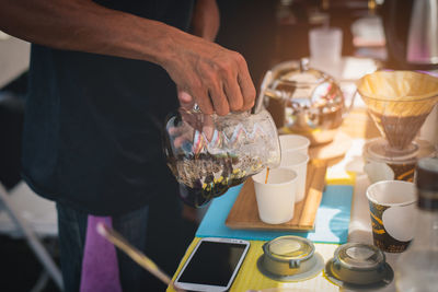 Midsection of man pouring coffee in cup at table