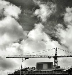 Low angle view of crane against cloudy sky