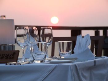 Glasses on table at restaurant during sunset