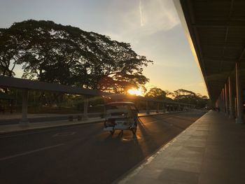 Road by city against sky during sunset