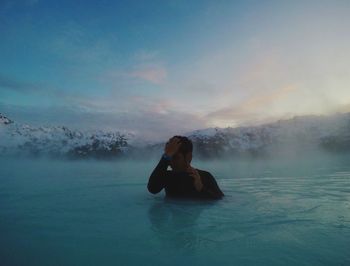 Man relaxing in swimming pool against sky