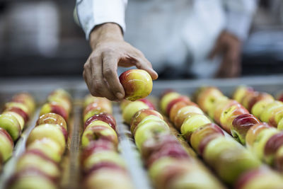 Worker taking apple from conveyor belt in factory