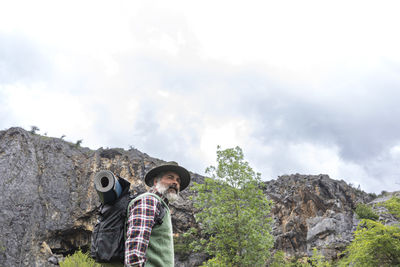 Rear view of man standing on mountain against sky